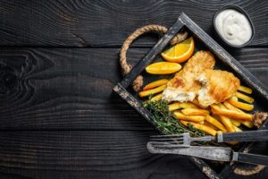battered-fish-chips-dish-with-french-fries-tartar-sauce-wooden-tray-black-wooden-background-top-view-copy-space_new